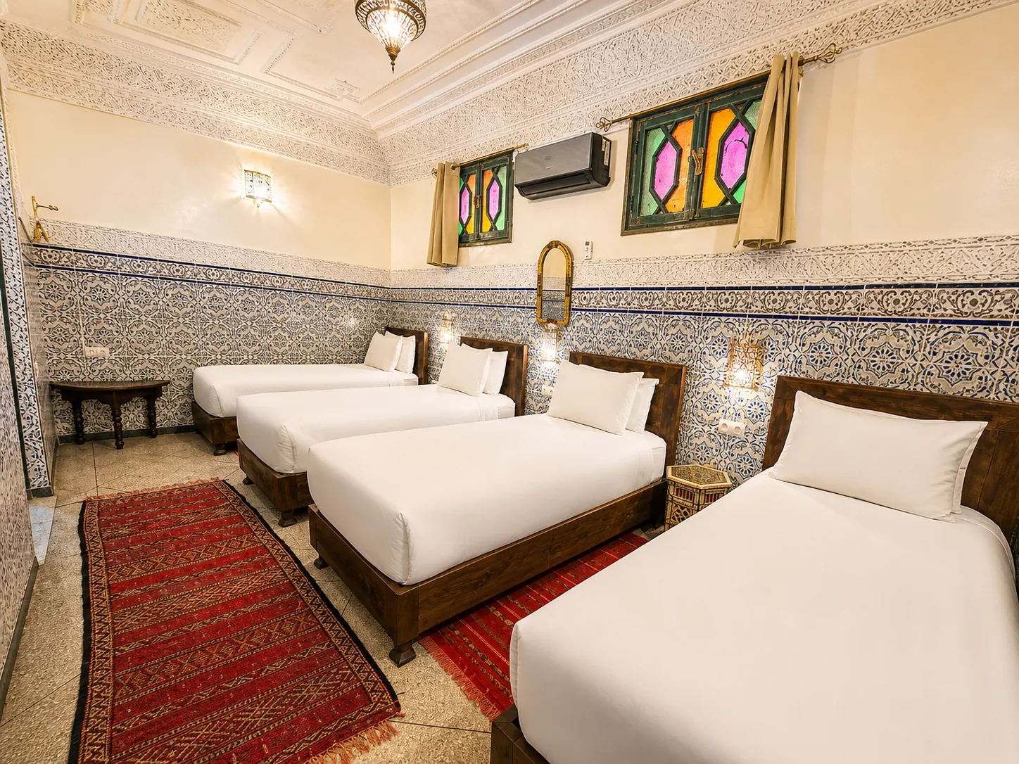 Jannat quadruple room at Riad Tasneem with four dark-wood beds and cream walls