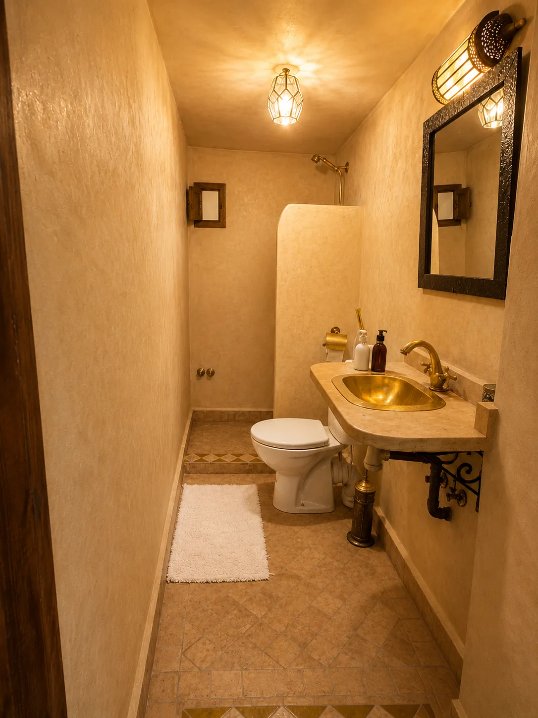 Sabah ensuite bathroom with tadelakt walls in ochre, brass washbasin, walk-in shower and oriental lantern overhead
