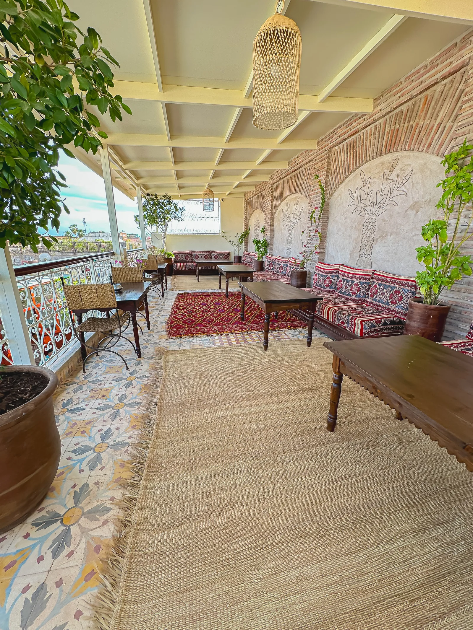Covered rooftop lounge at Riad Tasneem with Moroccan seating, kilim cushions and views over the medina