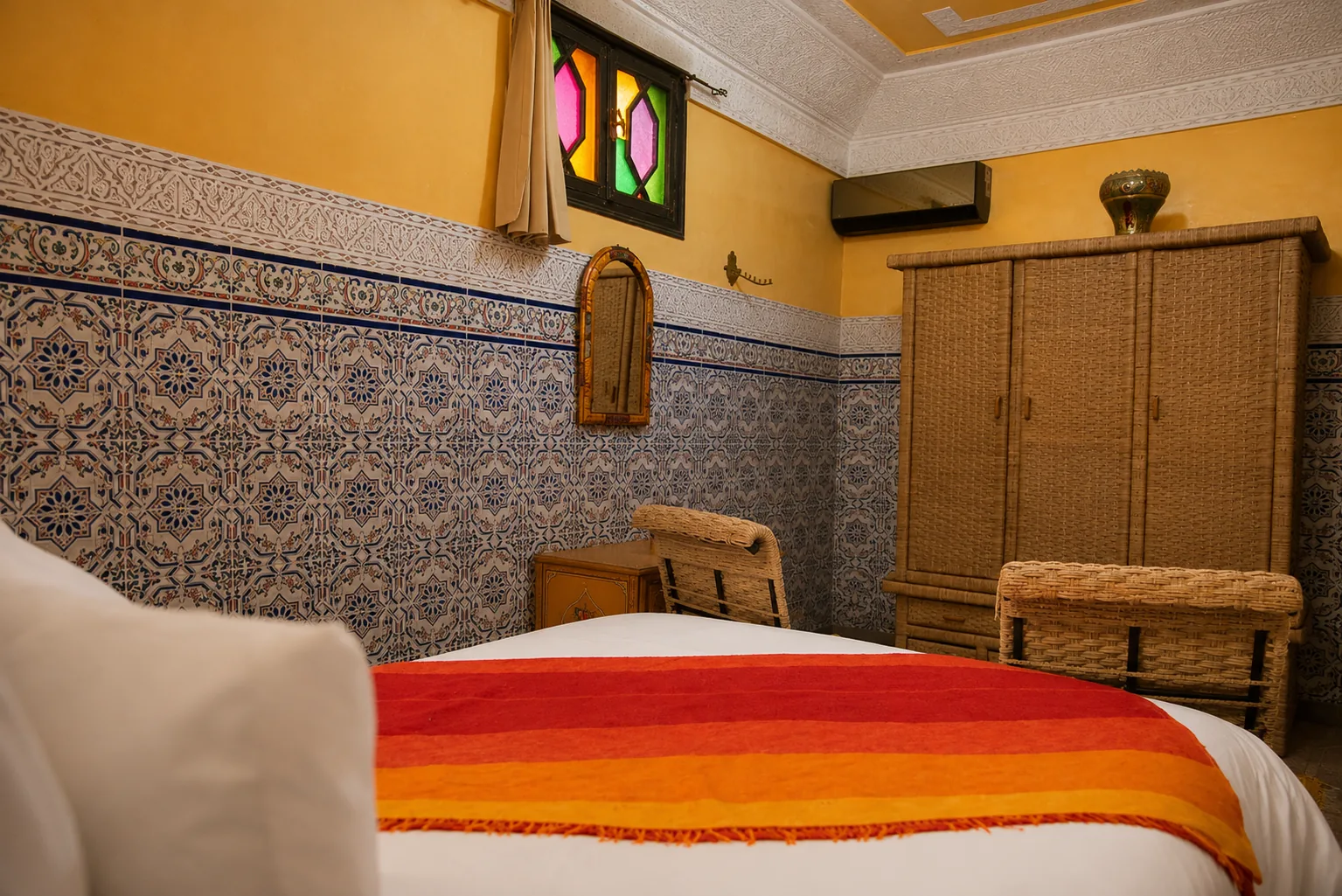 Yasmin room: wide angle view showing the intricately carved stucco ceiling, oriental lamp, carved cabinet with mirror and the stained-glass door to the patio